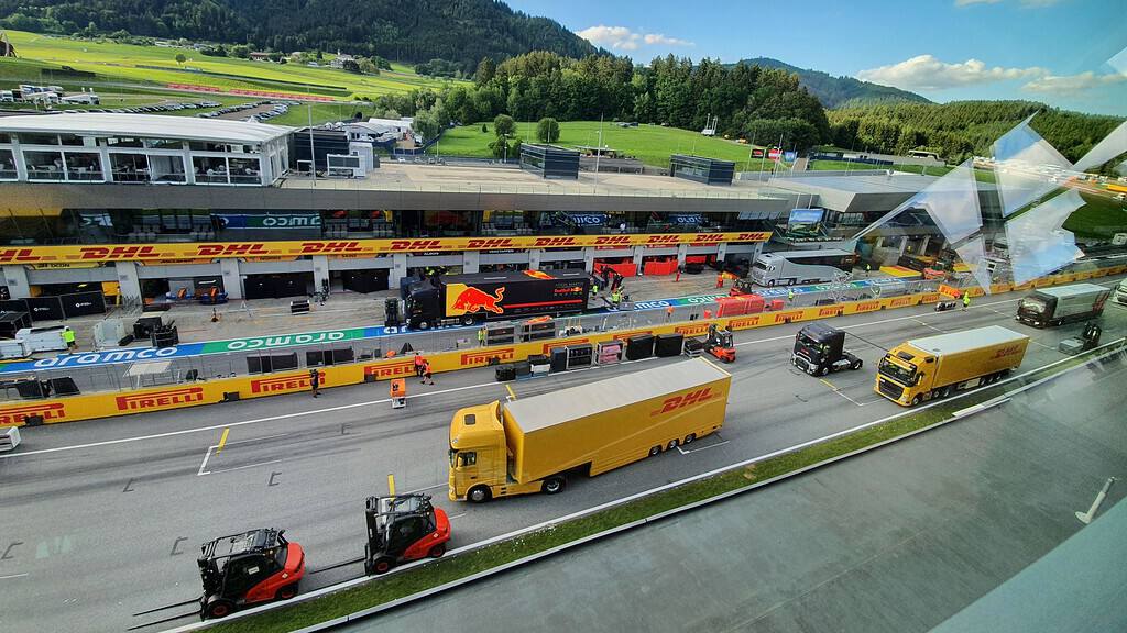 Camions DHL, Red Bull, Mercedes et Haas dans le paddock d'un circuit de F1